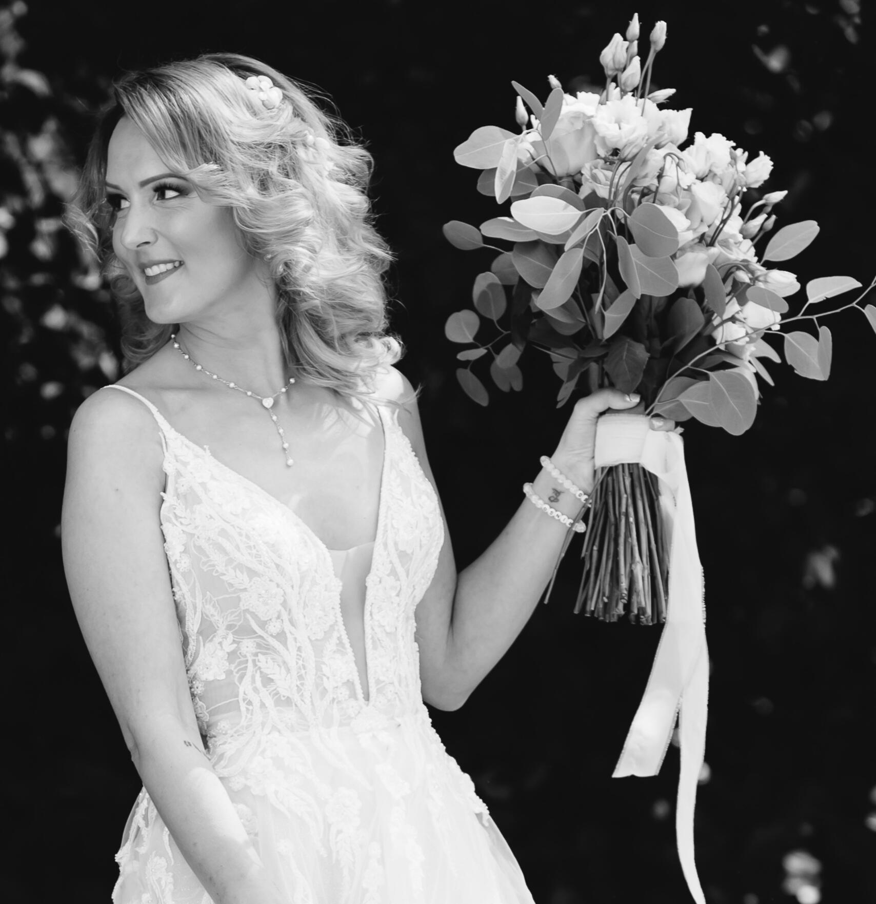 Elegantni crno-beli bridal portret mlade sa buketom na Salašu Zvonko Bogdan Crno-beli portret mlade koja drži venčani buket i osmehuje se tokom venčanja